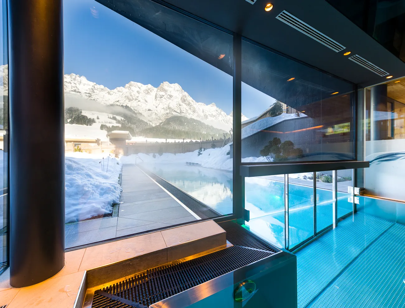 Innen-Außenpool mit Bergblick und verschneiter Landschaft im luxuriösen Wellnessresort