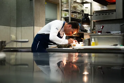 Chef plating gourmet dish with precision in a professional kitchen