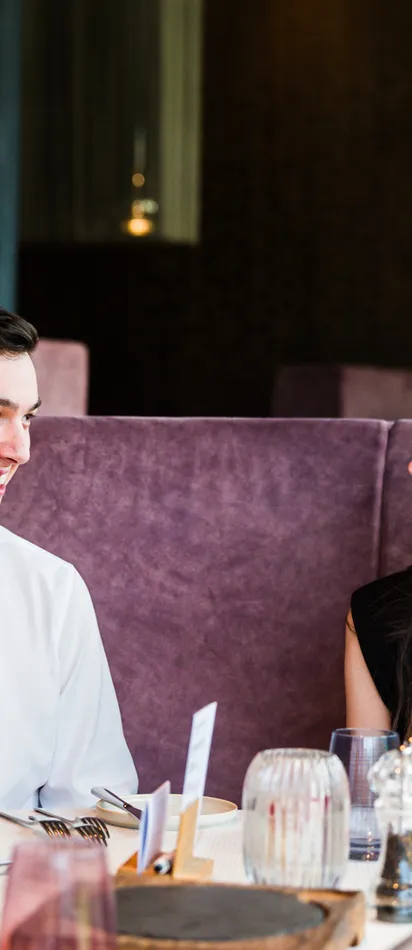 Smiling couple sitting at a table in a modern restaurant with purple booths