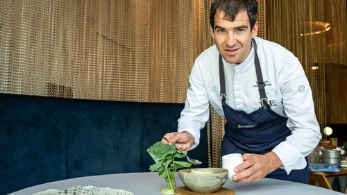 Koch garniert Gourmet-Suppe in einer Keramikschüssel im Fine-Dining-Restaurant