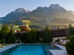 Außenpool eines Hotels mit Bergblick in den österreichischen Alpen bei Sonnenaufgang