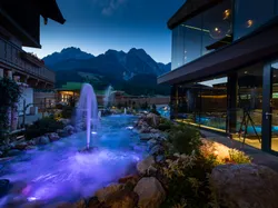 Luxury hotel spa with illuminated outdoor pool and mountain view at dusk