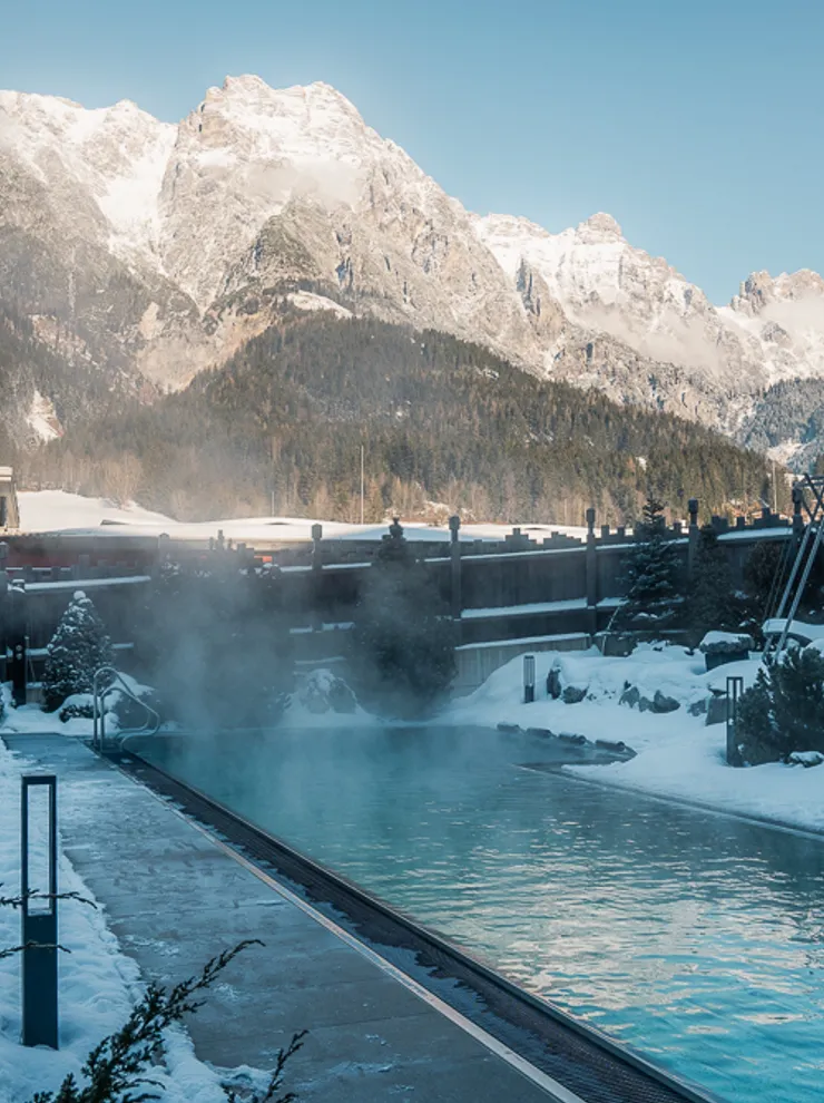 Outdoor thermal pool in snowy alpine resort with mountain view