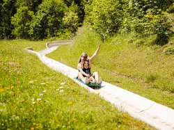 Mutter und Tochter flitzen die Sommerrodelbahn in Saalfelden Leogang hinunter ins Tal. 