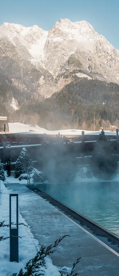 Outdoor thermal pool in snowy alpine resort with mountain view