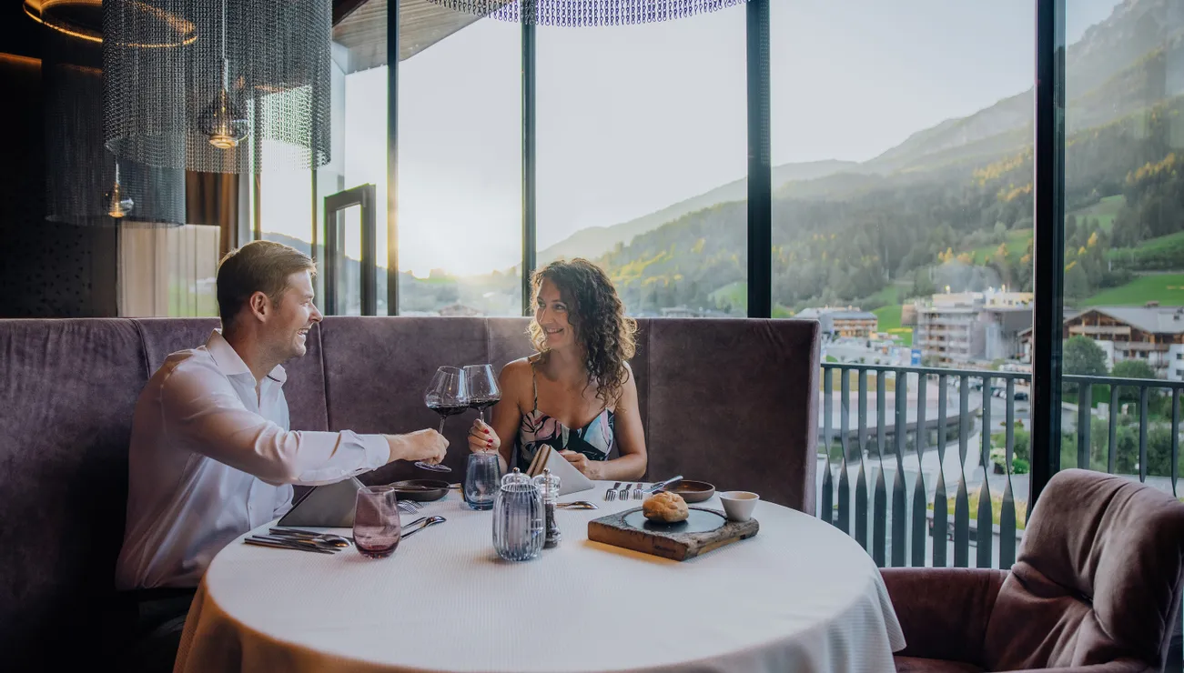 Paar genießt romantisches Abendessen mit Wein im Restaurant mit Bergblick
