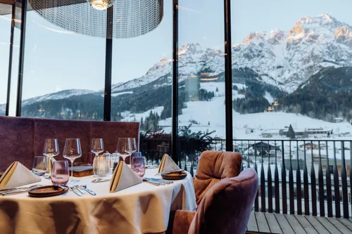 Eleganter Restauranttisch mit Bergblick durch große Glasfenster