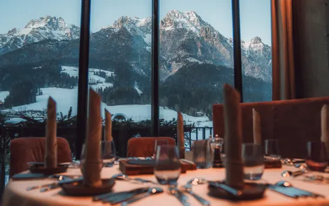 Elegant restaurant table set with view of snow-covered Alps through large window