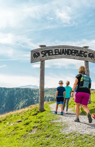 Family hiking on the Spielewanderweg trail in the Alps under sunny skies