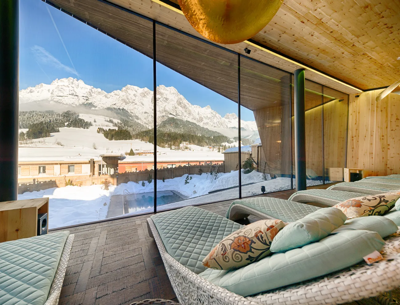 Ruheraum im Spa mit Liegestühlen und Blick auf schneebedeckte Alpen