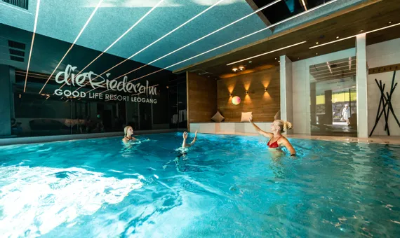 Frauen spielen mit einem Ball im Innenpool des Good Life Resort Leogang