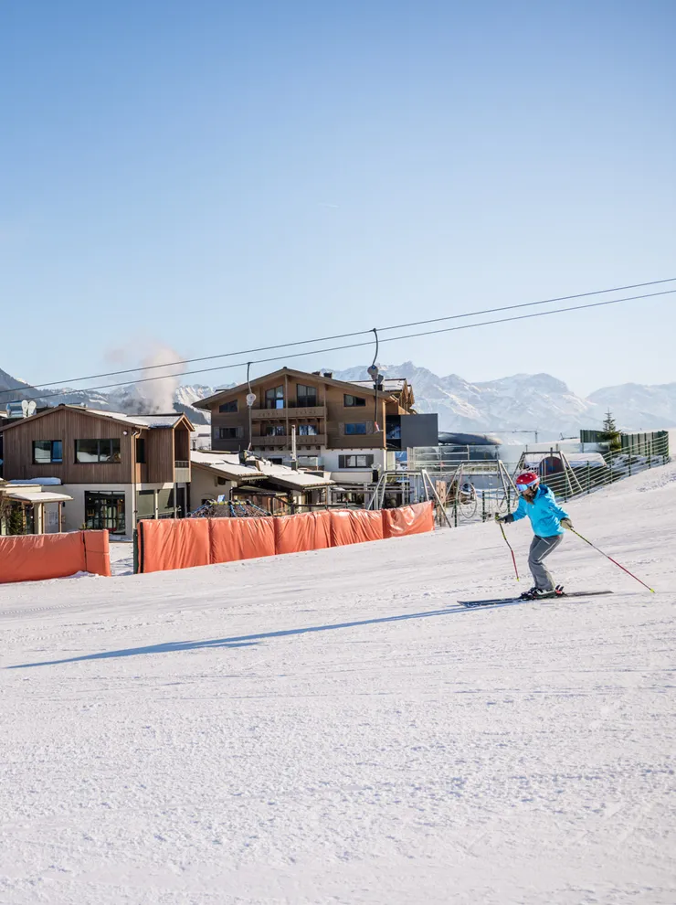 Skifahrer vor dem Good Life Resort Leogang mit schneebedeckten Alpen im Hintergrund
