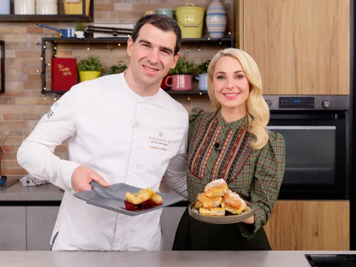 Koch und Frau präsentieren Teller mit Kaiserschmarrn und Dessert in moderner Küche