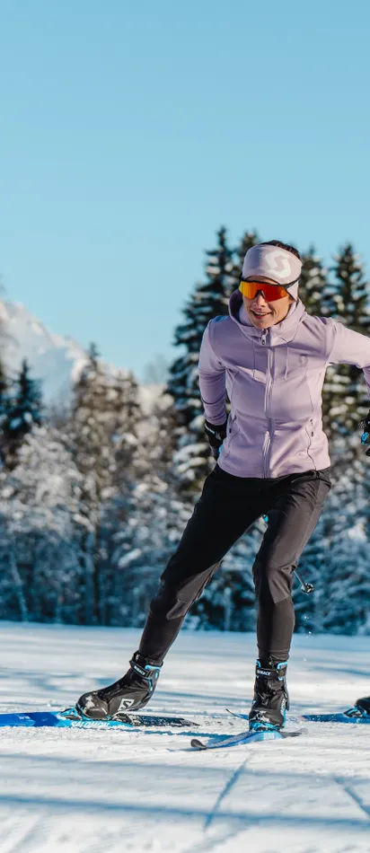 Zwei Personen beim Langlaufen auf verschneiter Loipe mit Alpen im Hintergrund