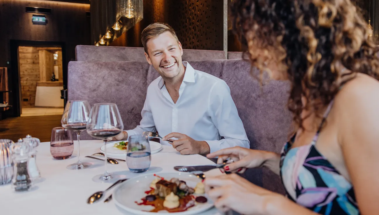 Lächelndes Paar genießt ein Gourmetessen mit Wein in einem modernen gehobenen Restaurant