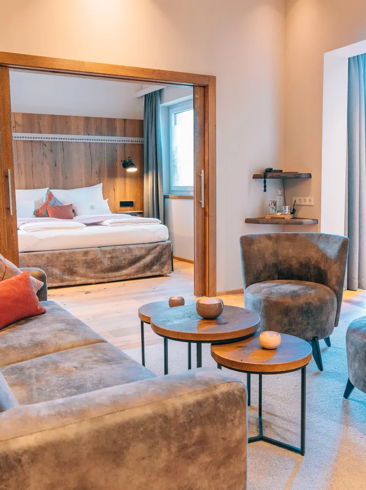 Moderne Hotelsuite mit Lounge-Bereich, Samtsesseln und gemütlichem Bett im natürlichen Licht