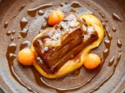 Geschmortes Schweinebauch mit Kürbispüree und Melonenkugeln in reichhaltiger Glasur