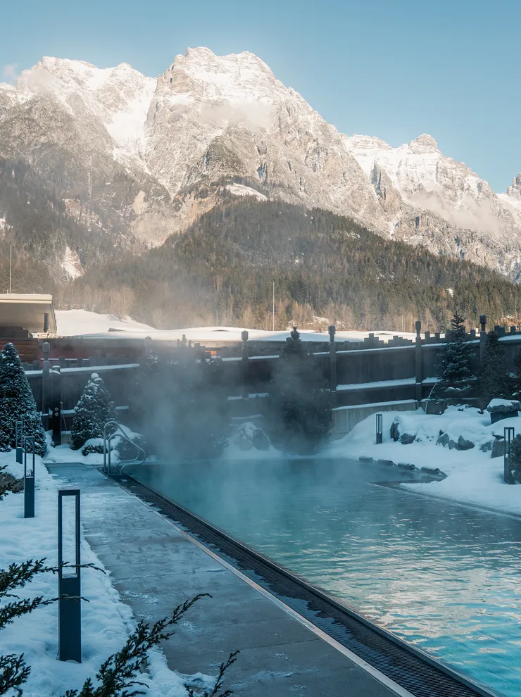 Outdoor thermal pool in snowy alpine resort with mountain view
