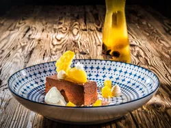Schokoladendessert mit Mango und Sahnetupfen in dekorativer Schale auf Holztisch