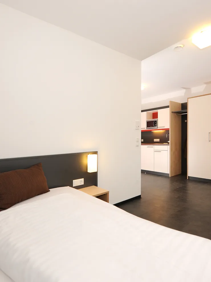 Modernes Studentenapartment mit Bett, Kochnische, Kleiderschrank und Schreibtisch