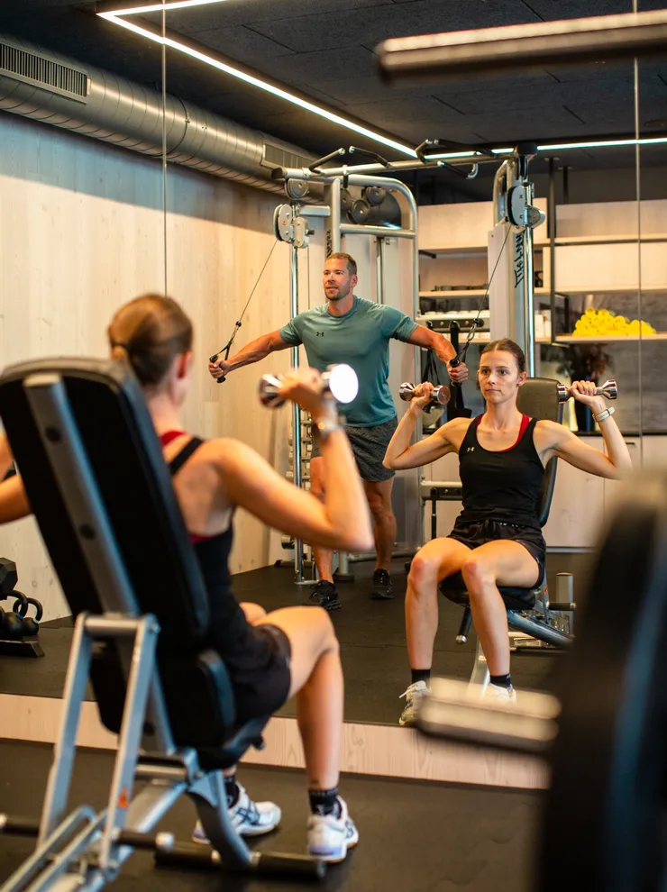 Mann und Frau machen Krafttraining in einem modernen Fitnessstudio mit Spiegeln