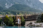 Paar im Bademantel am Spa-Pool in den Bergen mit Alpenwald im Hintergrund
