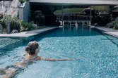 Frau schwimmt im Außenpool eines Luxushotels mit Bergblick