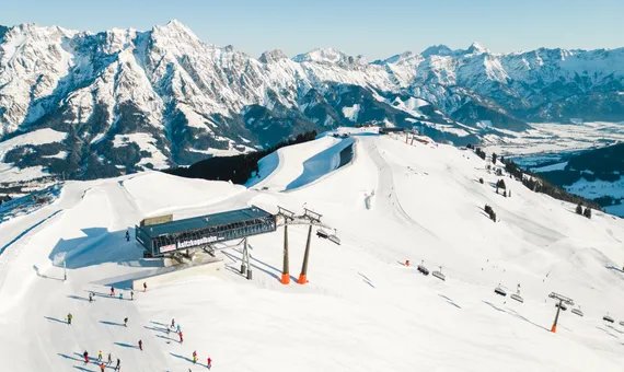 Skiers on snowy slopes near Asitzkogelbahn lift with Austrian Alps in the background