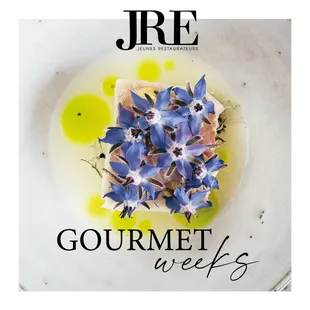 Gourmetgericht mit essbaren blauen Blüten und Kräuteröl für JRE Gourmet Weeks