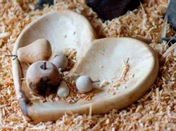 Heart-shaped wooden bowl with small woodturned items on wood shavings