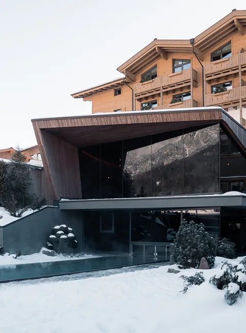 Modern alpine hotel with outdoor pool surrounded by snow in a winter landscape