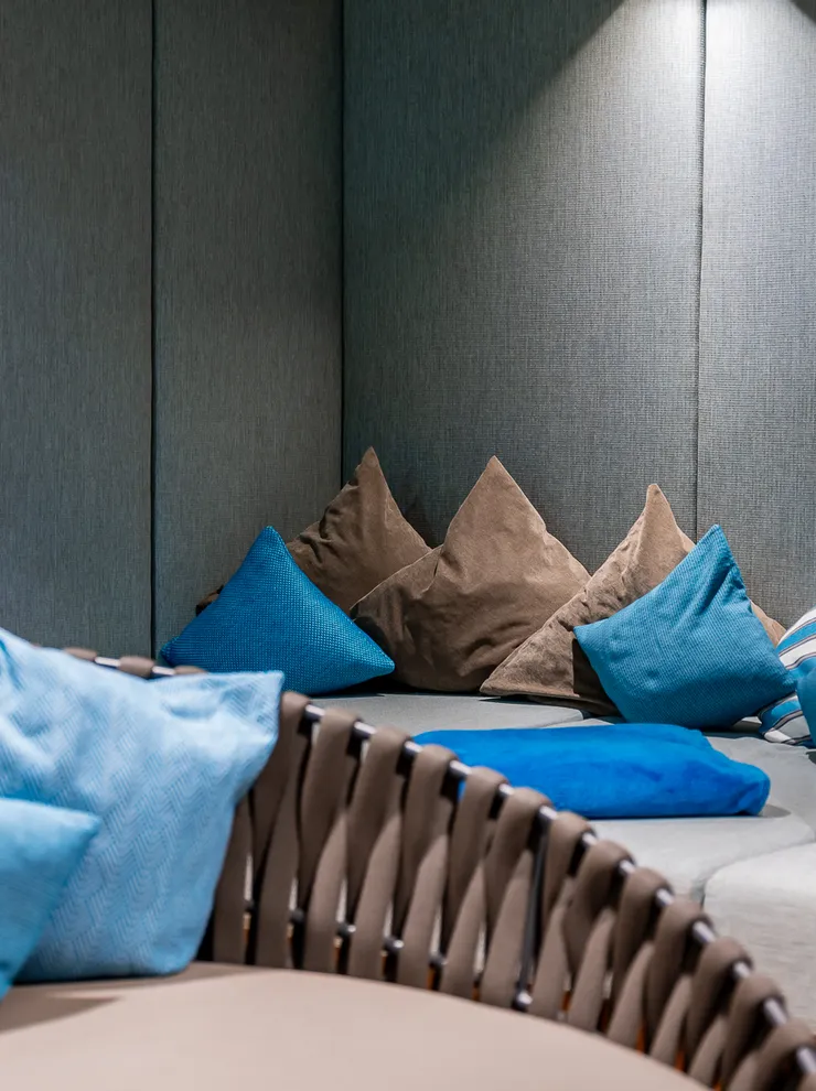 Gemütlicher Spa-Loungebereich mit blauen und braunen Kissen, sanfter Beleuchtung und Bücherregal