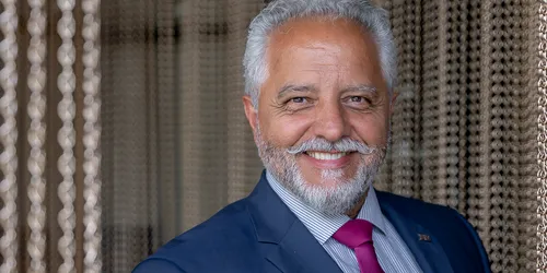 Lächelnder älterer Geschäftsmann im blauen Anzug mit roter Krawatte vor moderner Vorhangkette