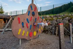 Kind spielt an bunter Kletterwand mit Griffen auf einem Außenspielplatz