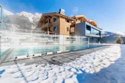 Luxury alpine hotel with outdoor heated pool and snow-covered ground