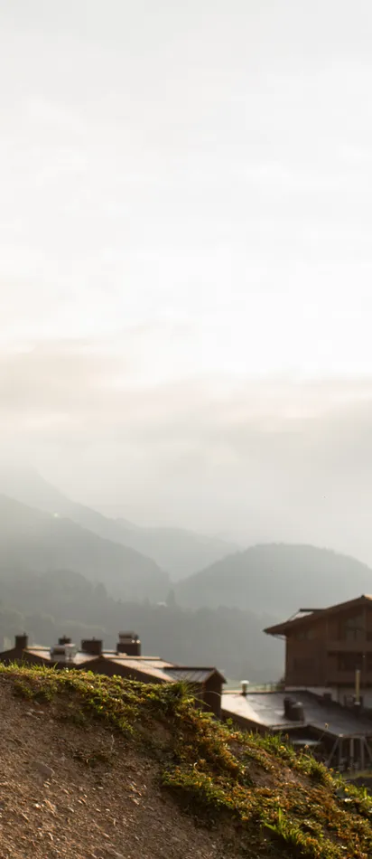 Mountainbikerin in pinkem Outfit springt auf Dirt-Trail bei Sonnenuntergang nahe Alpendorf