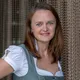 Woman in traditional Bavarian dirndl dress smiling in front of chain curtain