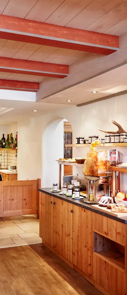 Breakfast buffet with fresh bread, fruit, and cold cuts in an alpine hotel