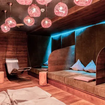 Modern spa relaxation room with warm lighting, hanging chairs and cushioned lounge areas