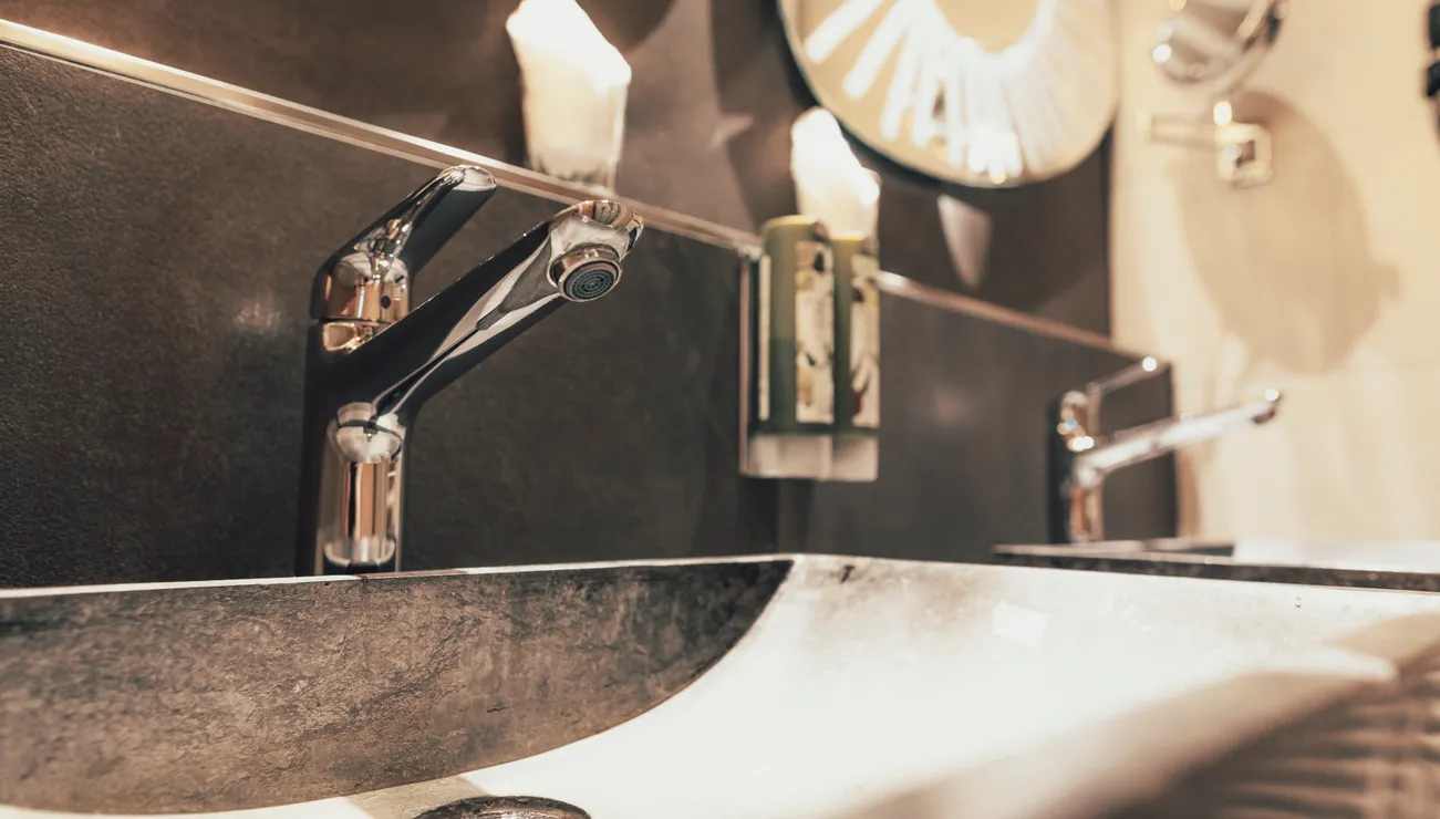 Moderne Badezimmerarmaturen mit Spiegel und Seifenspender an der Wand