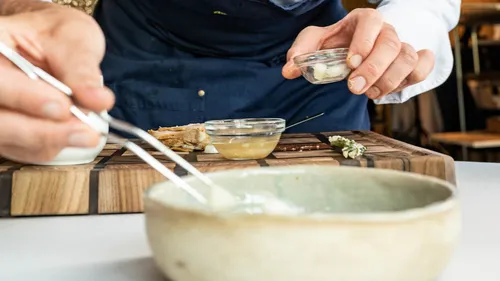 Koch richtet Gourmetgericht mit Pinzette in moderner Restaurantküche an