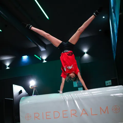 Kind macht Handstand auf gepolstertem Sprunggerät im Indoor-Trampolinpark Riederalm