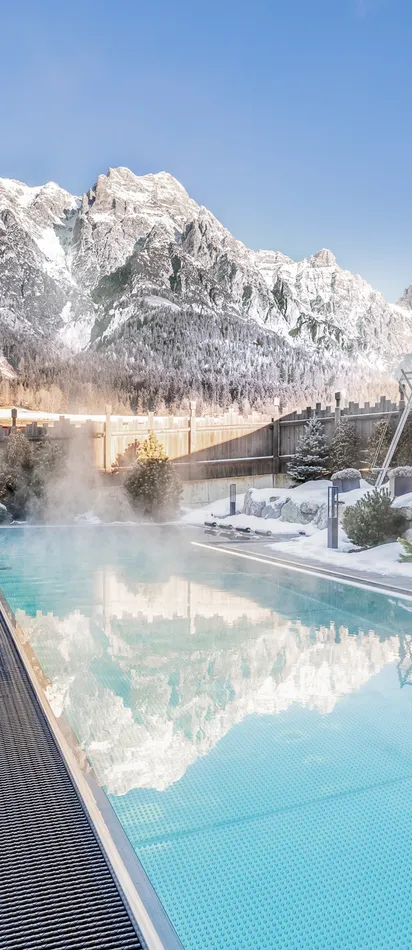 Beheizter Außenpool im verschneiten Alpenresort mit Bergblick