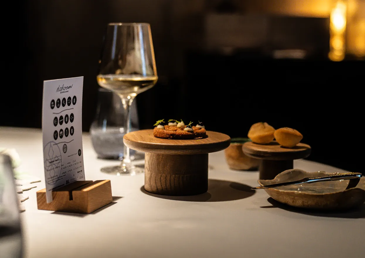 Gourmet appetizers served on wooden stands with wine glasses on a fine dining table