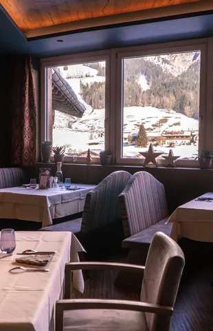Gemütliches Alpenrestaurant mit Blick auf schneebedeckte Berge durch große Fenster