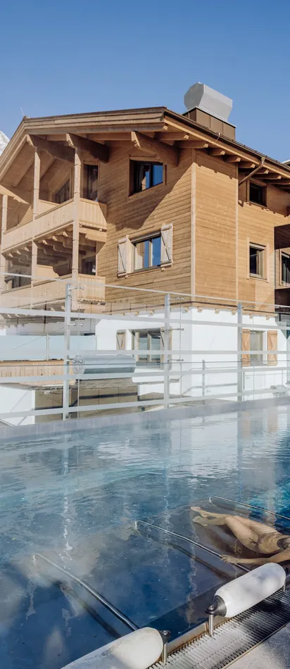 Woman relaxing in heated outdoor pool at alpine resort with snowy mountain view