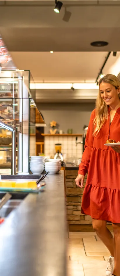 Woman in red dress choosing food at hotel buffet counter