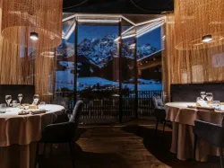 Elegant mountain view restaurant with candlelit tables and large windows overlooking snowy peaks