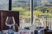 Eleganter Restauranttisch mit Weingläsern und Blick auf bergige Landschaft