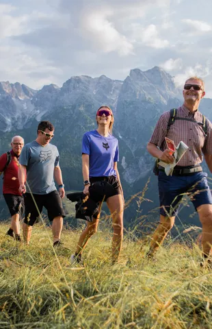 Gruppe von Wanderern auf einem grasbewachsenen Pfad mit malerischem Bergblick im Hintergrund